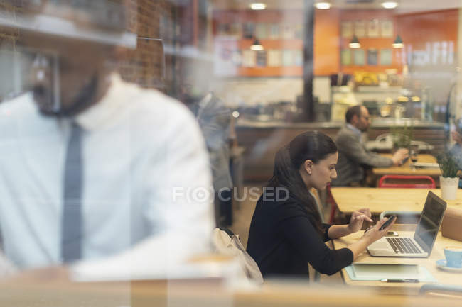 Donna d'affari focalizzata che lavora a computer portatile in caffè — Foto stock