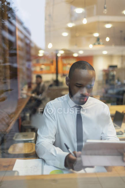 Бізнесмен, використовуючи цифровий планшет, працює у вікні кафе — стокове фото