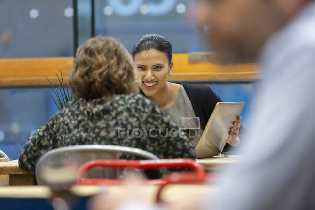 Бізнес-леді з цифровим планшетом розмовляють, працюють в кафе — стокове фото