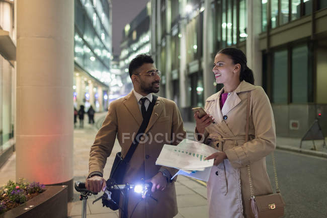 Empresários discutindo papelada na calçada urbana à noite — Fotografia de Stock