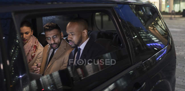 Uomini d'affari sul sedile posteriore del taxi crowdsourced di notte — Foto stock