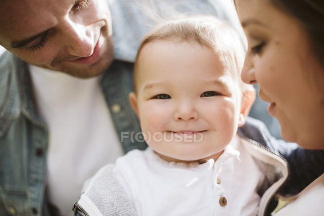 Батьки тримають милого хлопчика, дивлячись на камеру — стокове фото