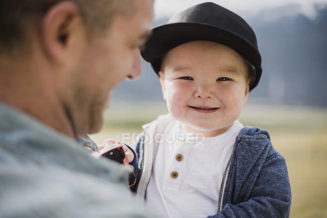 Portrait cute baby boy over father s shoulder — Stock Photo