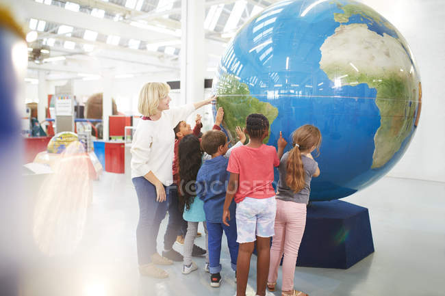 Вчителем та учнями, торкаючись великому глобусом в науковому центрі — стокове фото