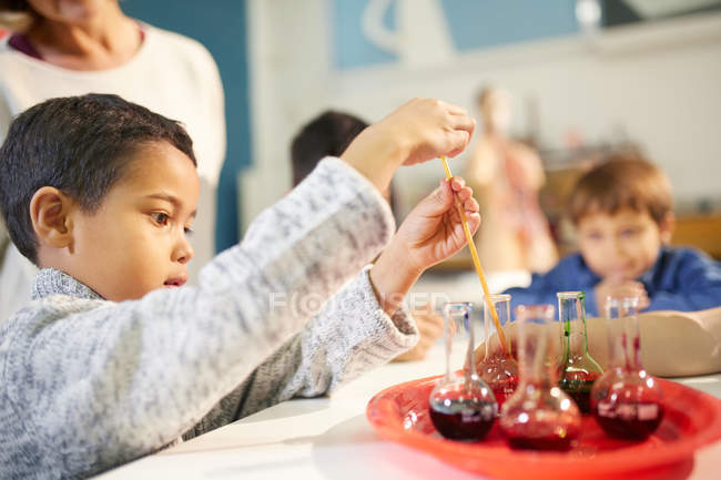 Curious boy using pipette in beaker at interactive exhibit in science center — Stock Photo