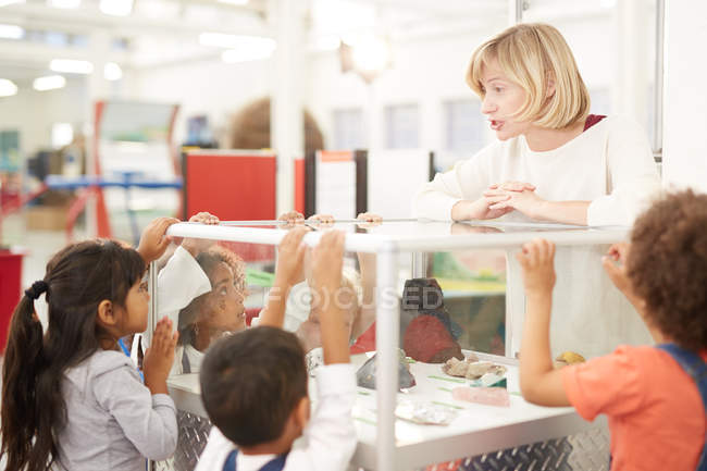 Teacher and students looking at rocks in display case in science center — Stock Photo