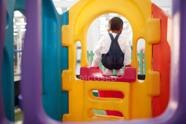 Хлопчик грає на слайді в приміщенні — стокове фото