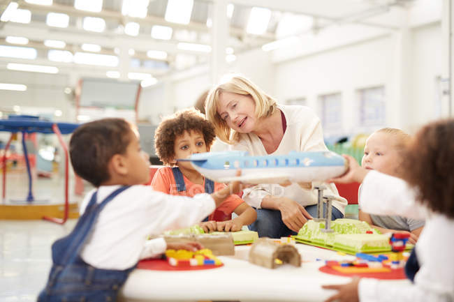 Teacher showing toy airplane to kids in science center — Stock Photo