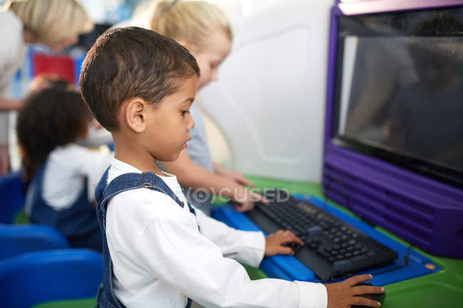 Цікавий хлопчик використовує комп'ютер — стокове фото