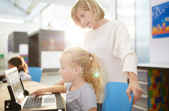 Teacher and schoolgirl using laptop in science center — Stock Photo