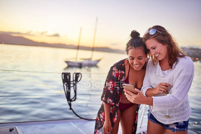 Молодые подруги используют смартфон на лодке — стоковое фото