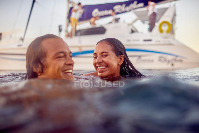 Glückliches junges erwachsenes Paar schwimmt in der Nähe von Katamaran im Meer — Stockfoto