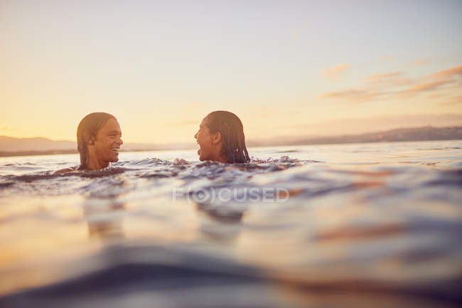Молодая пара плавает в океане на закате — стоковое фото