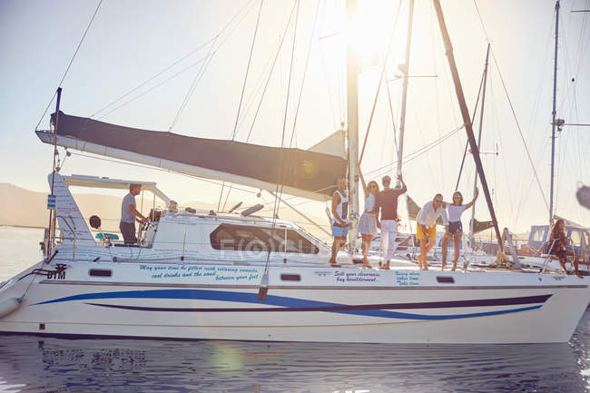 Portrait friends waving on catamaran in sunny harbor — Stock Photo