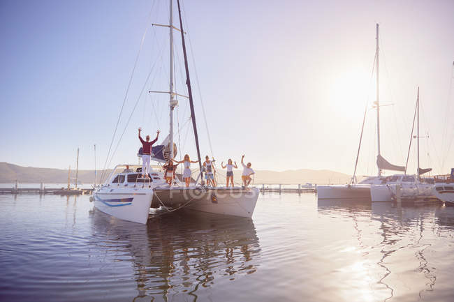 Portrait friends waving on catamaran in sunny harbor — Stock Photo