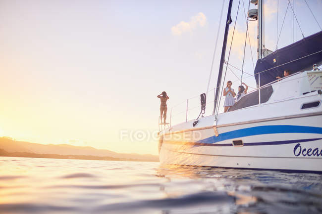 Vista de amigos descansando en catamarán al atardecer - foto de stock