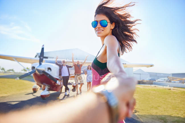 Personal perspective woman leading man by the hand toward prop airplane — Stock Photo