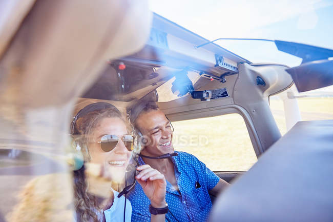 Piloto feliz y pareja copiloto volando avión - foto de stock