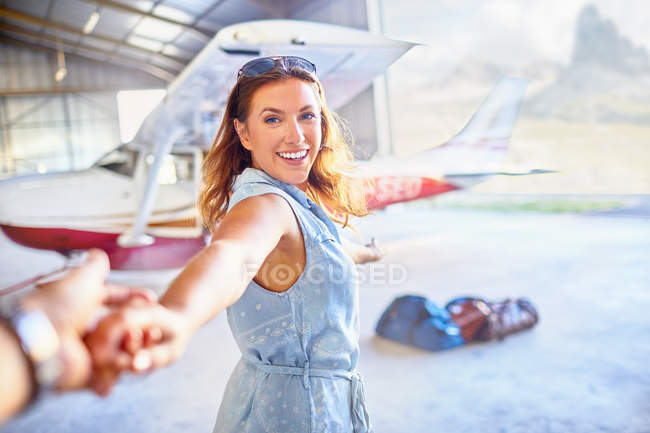 Personal perspective eager woman leading man by the hand toward small airplane — Stock Photo