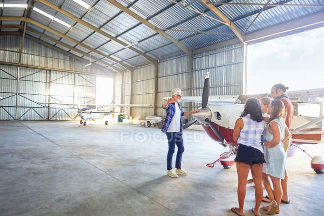 Pilot talking to friends at prop airplane in airplane hangar — Stock Photo