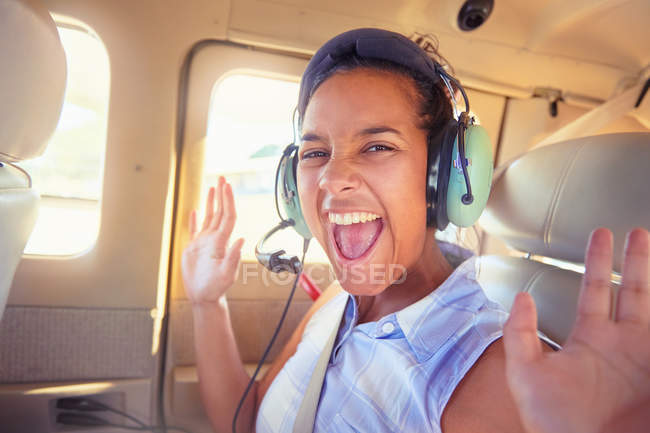 Portrait enthusiastic young woman with headphones riding in airplane — Stock Photo