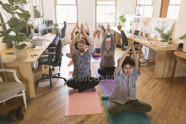 Creative business people practicing yoga in office — Stock Photo