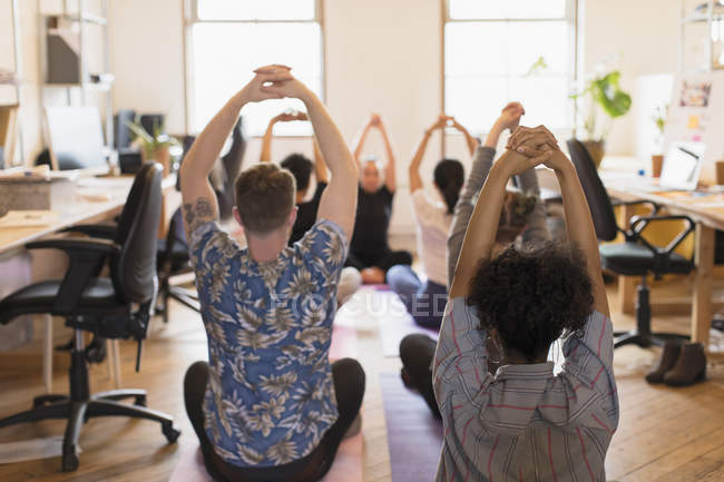 Творческие бизнесмены, практикующие йогу в офисе — стоковое фото