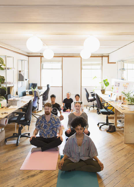 Спітнілі креативні бізнесмени медитують в офісі — стокове фото