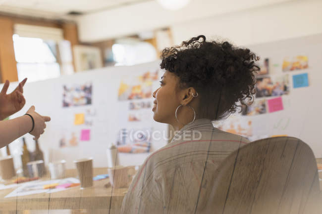 Креативна жінка-дизайнерка слухає колегу в офісі — стокове фото