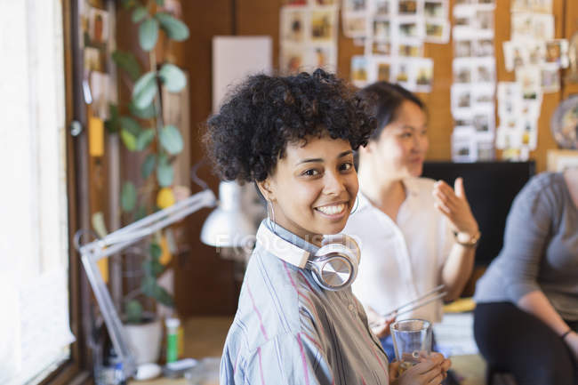 Retrato sonriente, mujer de negocios creativa con confianza con auriculares en la oficina - foto de stock