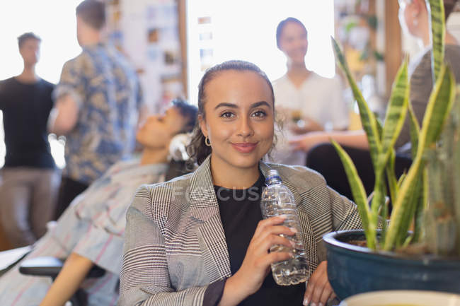 Retrato confiante empresária bebendo água engarrafada no escritório — Fotografia de Stock
