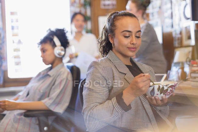 Creative businesswoman eating soup in office — Stock Photo