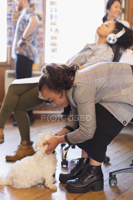 Creative businesswoman petting cute dog in office — Stock Photo