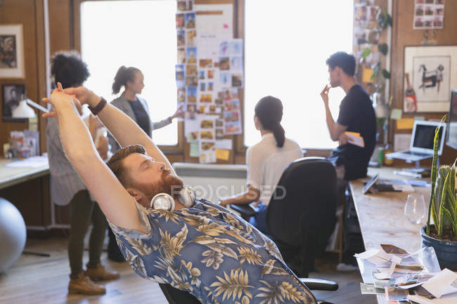 Diseñador masculino creativo estiramiento en la oficina - foto de stock