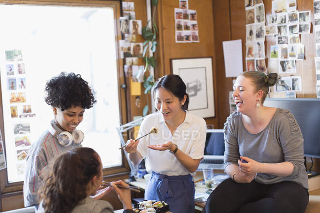 Творческие женщины-дизайнеры едят суши в офисе — стоковое фото