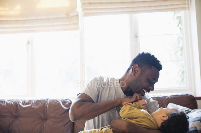 Игривый, любящий отец и сын обнимаются на диване в гостиной — стоковое фото
