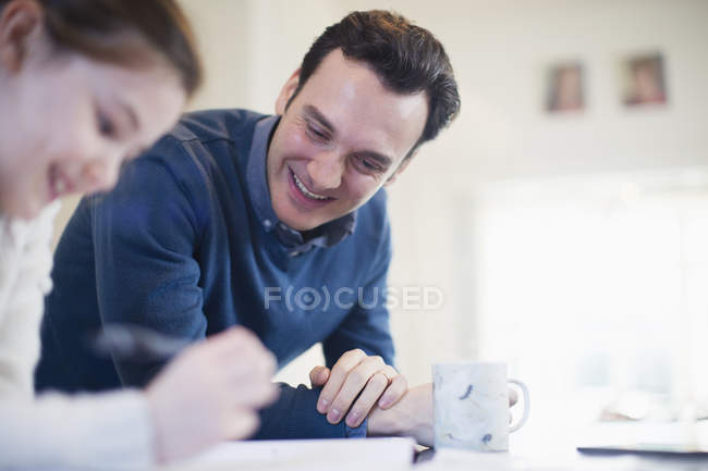 Smiling father helping daughter with homework — Stock Photo