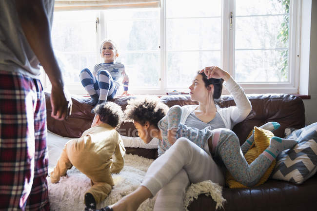 Multiethnische junge Familie im Pyjama spielt im sonnigen Wohnzimmer — Stockfoto