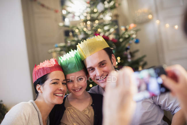 Happy family in paper crowns posing for photograph in Christmas living room — Stock Photo