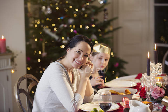 Retrato sonriente madre e hija disfrutando de la cena de Navidad con velas - foto de stock