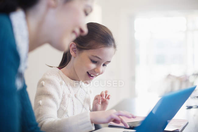 Sorrindo menina e mãe usando laptop — Fotografia de Stock