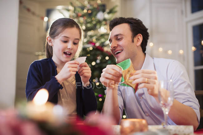 Отец и дочь открывают рождественский крекер на рождественском ужине — стоковое фото