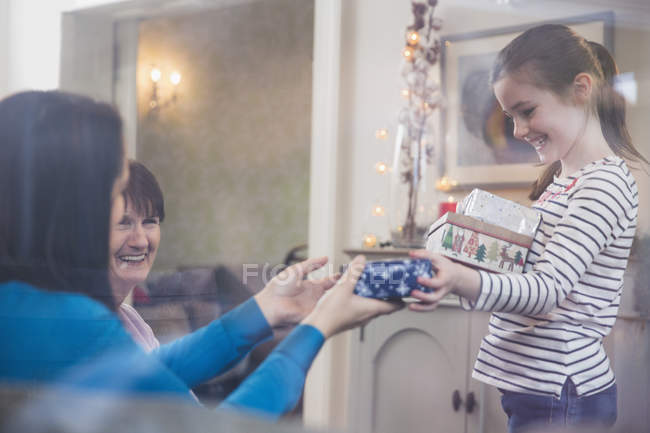 Figlia che distribuisce regali di Natale in soggiorno — Foto stock