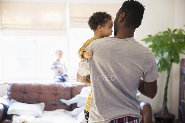 Pai segurando bebê filho na sala de estar — Fotografia de Stock