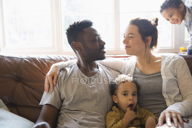 Affectueuse jeune famille multi-ethnique sur le canapé du salon — Photo de stock