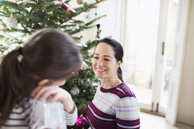 Lächelnde Mutter und Tochter im Gespräch am Weihnachtsbaum — Stockfoto