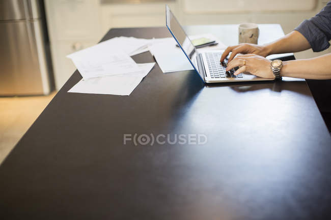 Hombre escribiendo, trabajando en el ordenador portátil en la mesa de comedor - foto de stock