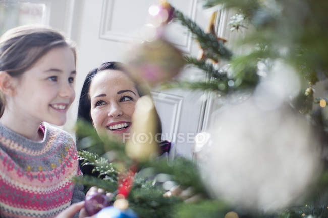 Счастливая мать и дочь украшают елку — стоковое фото