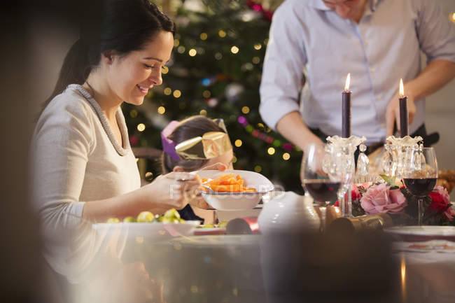 Woman serving carrots at candlelight Christmas dinner — Stock Photo