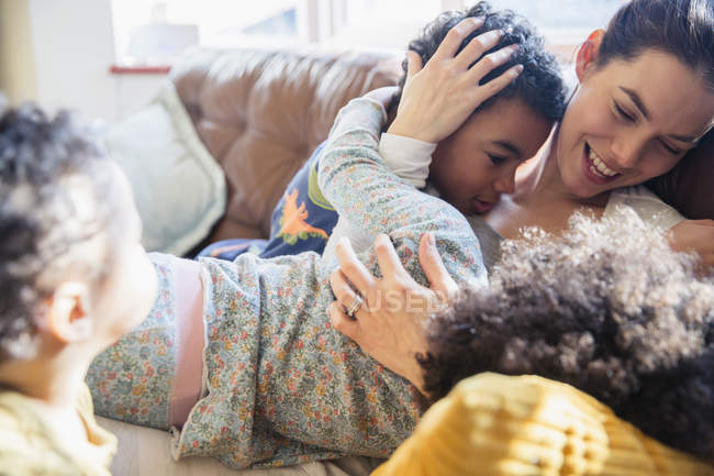 Mãe afetuosa e crianças abraçando no sofá — Fotografia de Stock